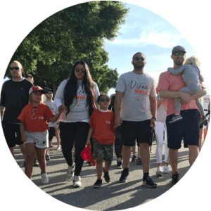 A group of people are participating in a community walk event, possibly "walking for a cure."