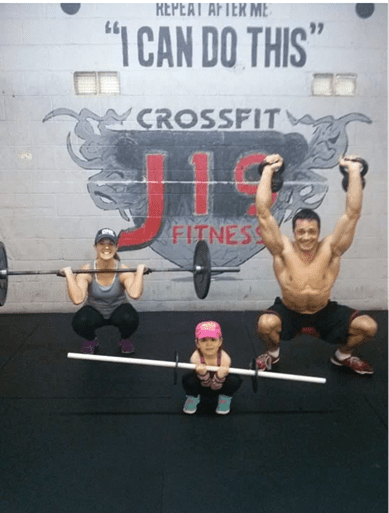 People doing weightlifting exercises at CrossFit J19 Fitness with motivational text on the wall.
